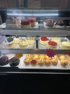 A display of cakes and pastries in a glass case.