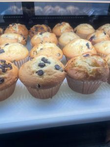 A display of chocolate chip muffins in a glass case.