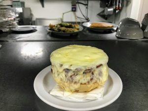 A cheesy dish is sitting on a plate in a kitchen.